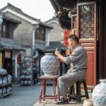 Ceramista dipinge a mano un grande vaso di porcellana in una strada di Jingdezhen