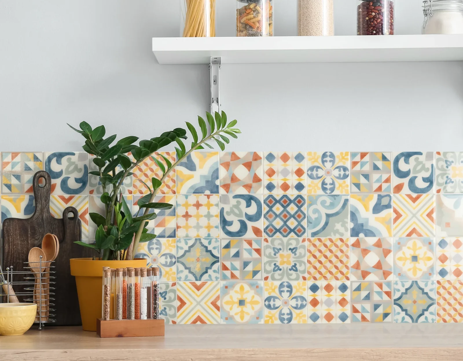Cucina luminosa con piastrelle decorative colorate, piano in legno, piante e contenitori per alimenti